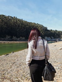 Rear view of woman standing in lake against sky