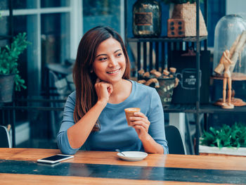 Portrait of smiling woman with coffee cup in restaurant