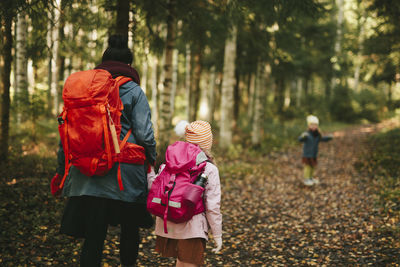 Rear view of people walking in forest