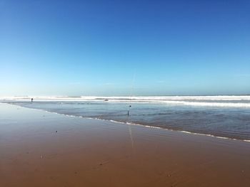 Scenic view of beach against clear blue sky