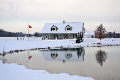 Snow covered houses and trees by building against sky