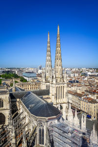 Aerial view of buildings in city against clear blue sky