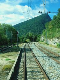 Railroad track by mountain against sky