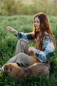 Side view of young woman sitting on field