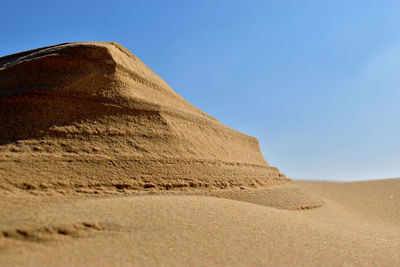 Low angle view of sand dunes against clear sky