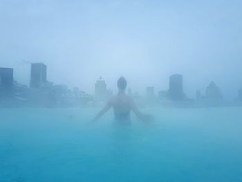 Silhouette of man in city against sky during foggy weather