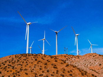 Windmill on field against clear blue sky