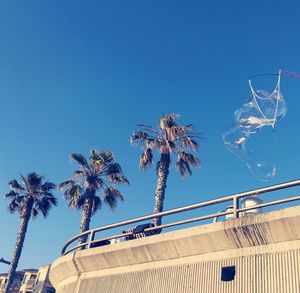 Low angle view of palm trees against clear blue sky