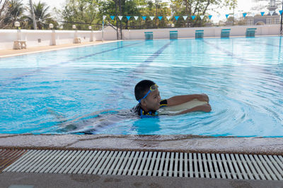 Full length of shirtless boy swimming in pool