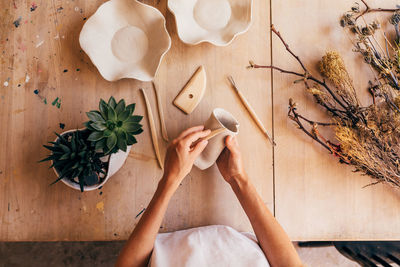 Midsection of woman making pottery on table in workshop