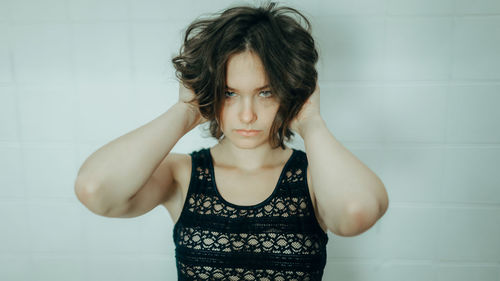 Portrait of young woman standing against wall