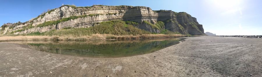 Rock formation by lake against sky