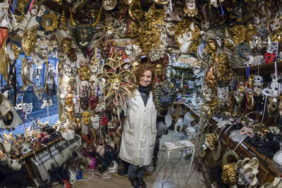 Portrait of woman smiling while standing amidst masks in store