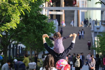 Rear view of a man carrying daughter on shoulders