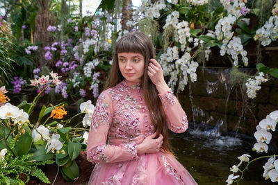 Woman standing by pink flowering plants