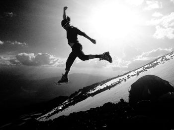 Silhouette man jumping on field during winter