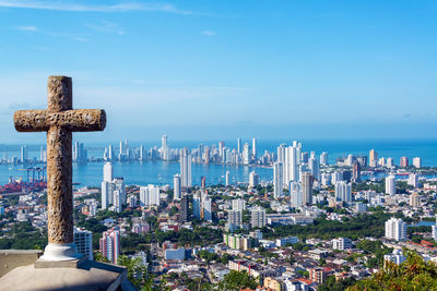 Stone cross with cityscape in background against sky