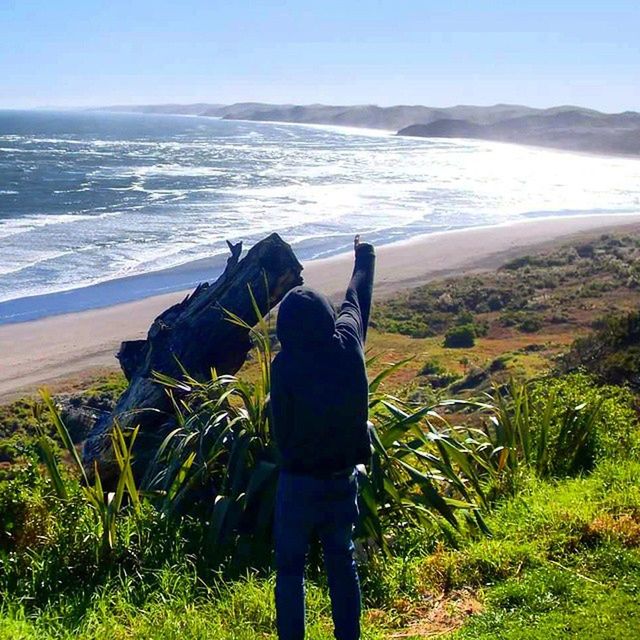 rear view, sea, horizon over water, water, lifestyles, leisure activity, standing, grass, men, person, tranquil scene, scenics, tranquility, nature, looking at view, beauty in nature, sky, full length