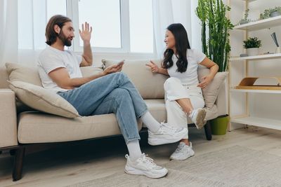 Side view of woman using mobile phone while sitting on sofa at home