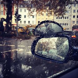 Close-up of wet car on road during rainy season