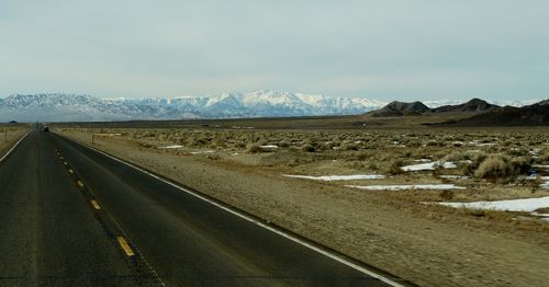 Road by railroad tracks against sky during winter