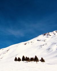 Scenic view of snow covered mountains against blue sky