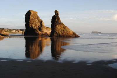 Rock formation on beach against sky