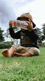 Side view of woman sitting on grassy field