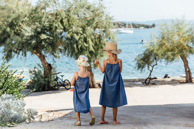 Boys standing on beach against trees