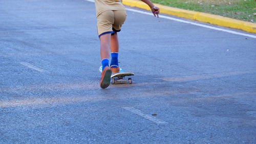 Low section of man skateboarding on road