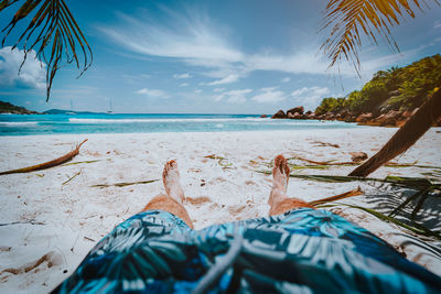 Low section of man on shore against sky