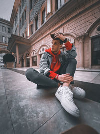 Full length of young man sitting in front of building