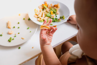 High angle view of baby girl holding food in plate on table