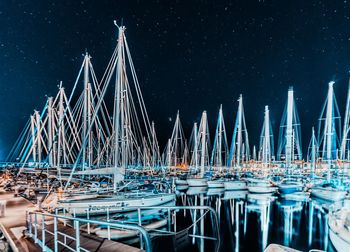 Sailboats moored in sea against sky at night