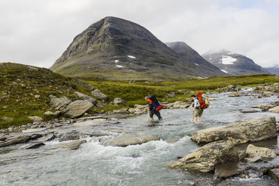 Hikers crossing mountain river