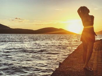 Woman standing on beach against sky during sunset