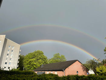 Rainbow over buildings in city against sky
