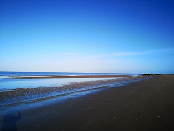 Scenic view of beach against clear blue sky