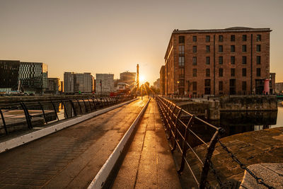 Railroad tracks amidst buildings against sky during sunset