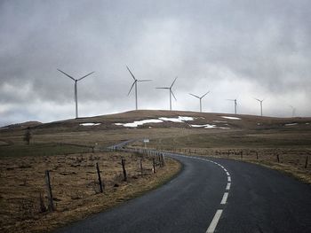 Wind turbines on field against sky