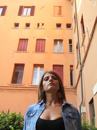 Low angle portrait of woman standing against building