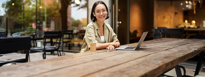 Young woman using mobile phone while sitting on table