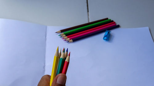 Close-up of hand holding colored pencils