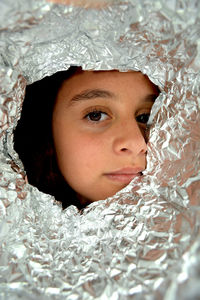 Portrait of girl looking through foil paper