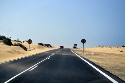 Car on road in desert against clear sky