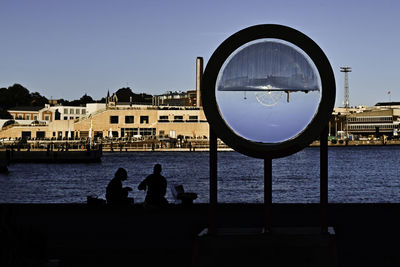 People by sea against clear sky
