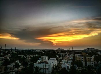 Cityscape against cloudy sky at sunset