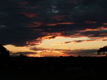 Silhouette landscape against dramatic sky during sunset