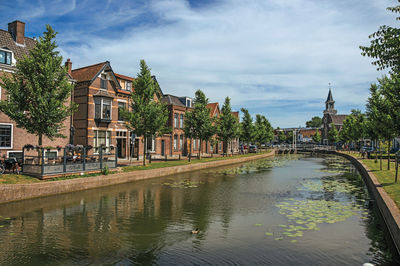 Canal amidst buildings against sky in city