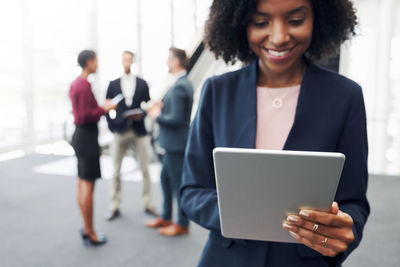 Young woman using mobile phone while standing on laptop